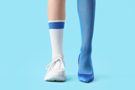 Legs of young woman in different stylish shoes on blue backgroundの写真素材