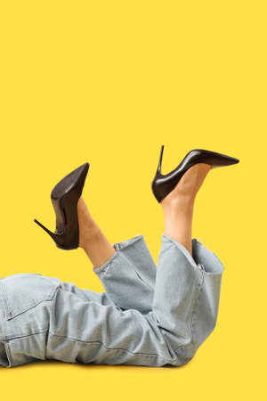 Legs of young woman in stylish black high heels on yellow backgroundの写真素材