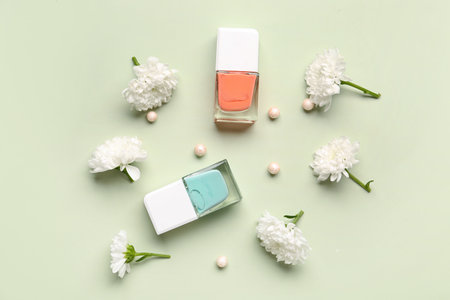Composition with stylish nail polishes, highlighter balls and beautiful chrysanthemum flowers on beige backgroundの写真素材