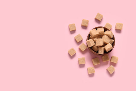 Bowl with brown cane sugar cubes on pink backgroundの写真素材