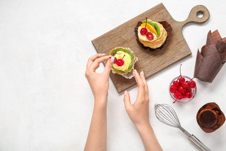Female confectioner decorating tasty cakes on white backgroundの写真素材