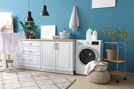 Laundry room interior with washing machine, white counters and clothes on drying rackの写真素材