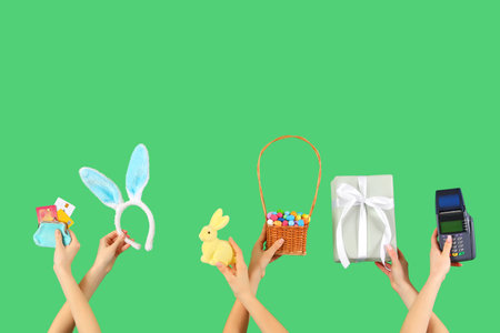 Women with payment terminal, credit cards, gift and Easter decor on green background. Online shoppingの写真素材