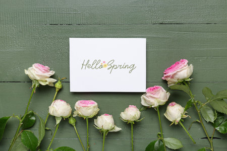 Greeting card with text HELLO SPRING and beautiful roses on green wooden backgroundの写真素材