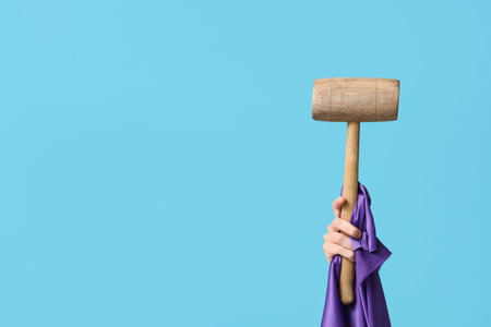 Female hand with wooden mallet and purple fabric on color background. Good Friday conceptの写真素材
