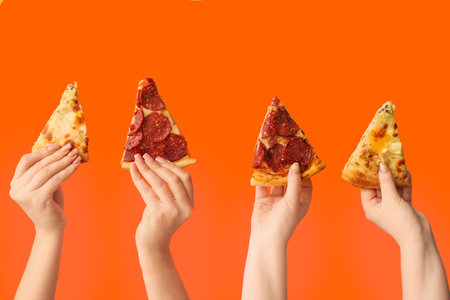 Many hands holding tasty pizza slices on orange backgroundの写真素材