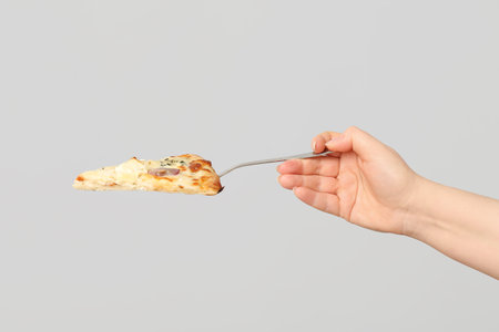 Female hand holding tasty pizza slice with spatula on white backgroundの写真素材