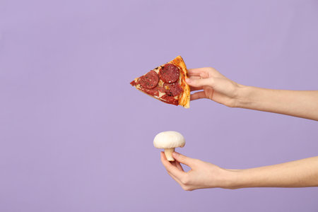 Female hands holding pizza slice and mushroom on lilac backgroundの写真素材