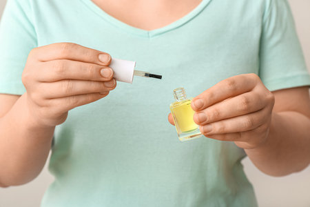 Woman holding bottle of cuticle oil on white background, closeupの写真素材