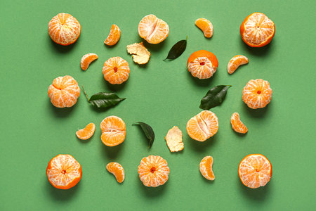 Fresh tangerines with peel and leaves on green backgroundの写真素材
