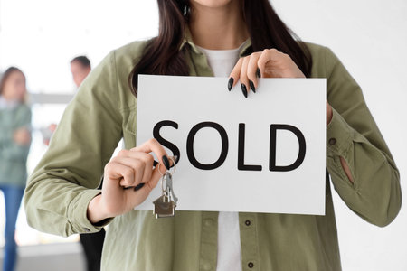 Young lesbian woman with keys from her new house and word SOLD, closeupの写真素材