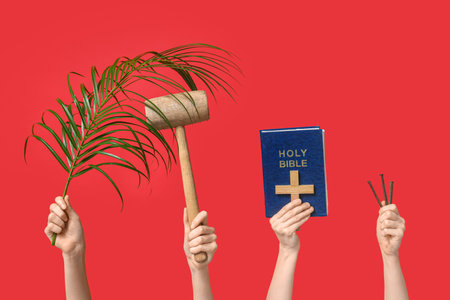 Female hands with Holy Bible, wooden mallet, palm leaf and nails on red background. Good Friday conceptの写真素材