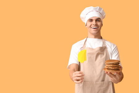 Young man with tasty homemade pancakes on yellow backgroundの写真素材