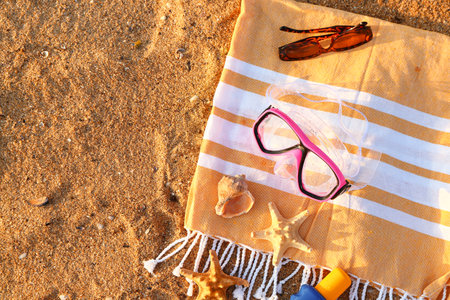 Swimming mask, towel, sunglasses and starfishes on sandの写真素材