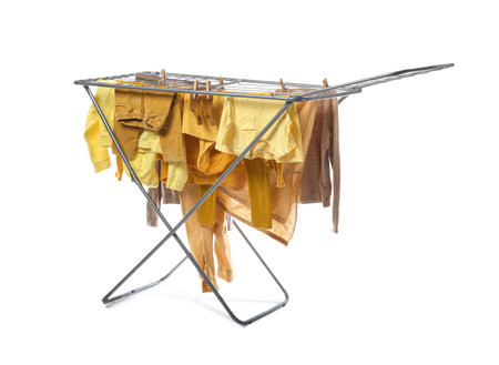 Clean children's clothes hanging on dryer against white backgroundの写真素材