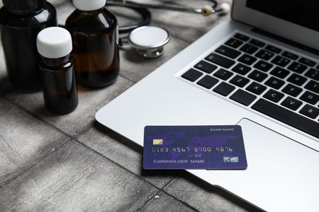 Laptop, credit card and items from first aid kit on grunge gray tile backgroundの写真素材