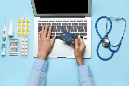 Female hands with items from first aid kit and laptop on blue backgroundの写真素材