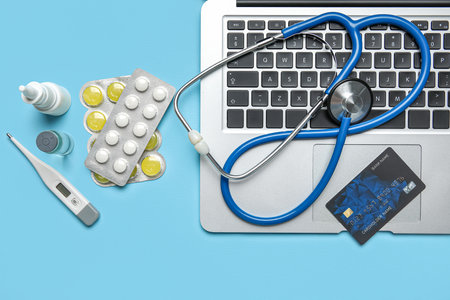 Credit card with items from first aid kit and laptop on blue backgroundの写真素材