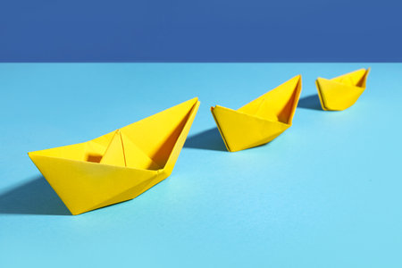 Yellow origami boats on color backgroundの写真素材