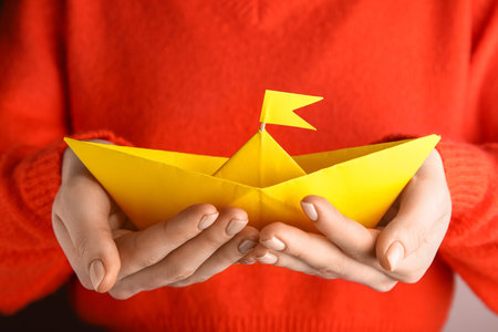 Woman holding yellow origami boat, closeupの写真素材