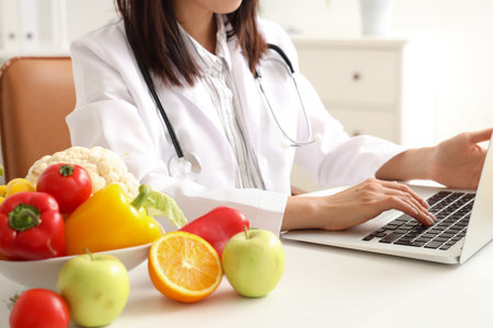 Female nutritionist working with laptop at table in office, closeupの写真素材