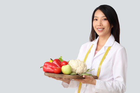 Female Asian nutritionist with healthy food on light backgroundの写真素材