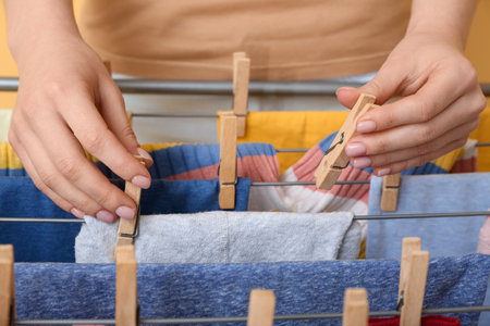 Woman clean baby clothes on dryer, hanging closeupの写真素材