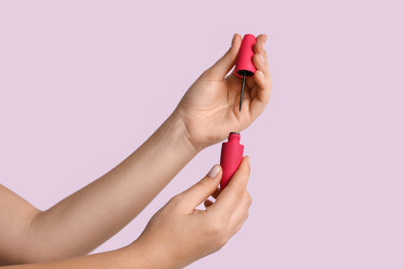 Female hands with eyeliner on lilac background, closeupの写真素材