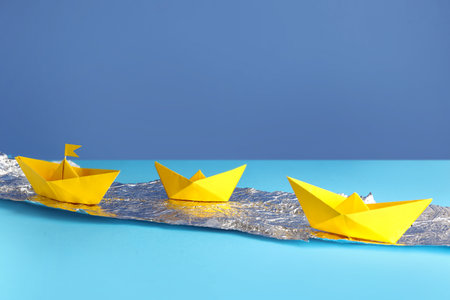 Yellow origami boats with foil on color backgroundの写真素材