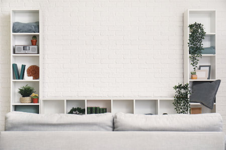 TV stand with books and plants near white brick wall in living roomの写真素材