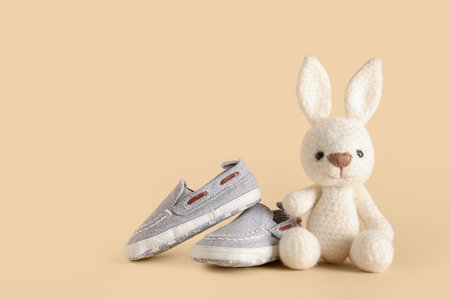Stylish baby shoes with cute toy on beige backgroundの写真素材