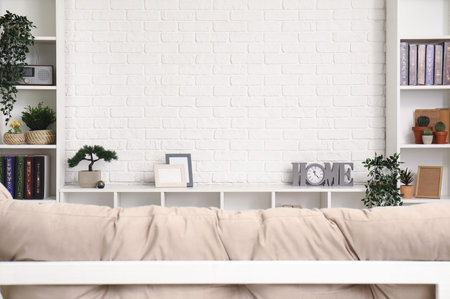 TV stand with books and plants near white brick wall in living roomの写真素材