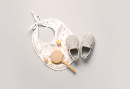 Stylish baby shoes with bib and rattle on gray backgroundの写真素材