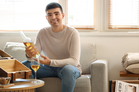 Young man with bottle of wine at homeの写真素材