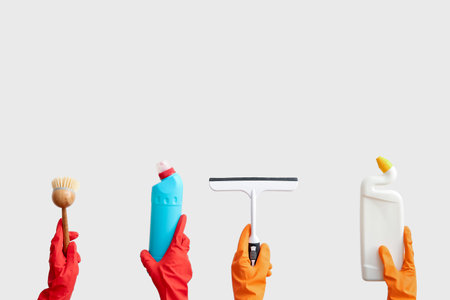 Female hands in rubber gloves holding cleaning supplies on beige backgroundの写真素材