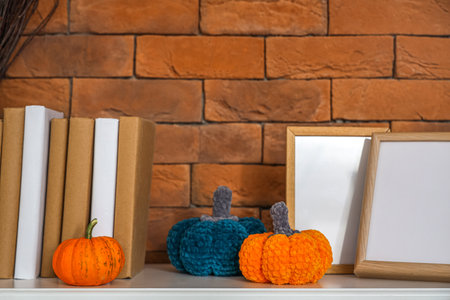Pumpkins with photo frames and books on mantelpiece near brick wallの写真素材