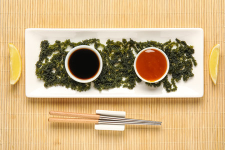 Composition with plate of healthy seaweed, sauces and chopsticks on bamboo matの写真素材