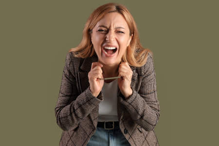 Scared mature woman on green background