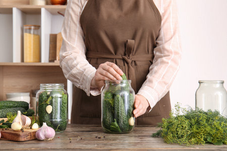 Woman preparing fresh cucumbers for canning at table in kitchenの写真素材