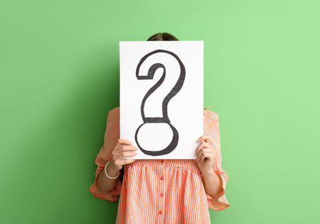 Young woman holding paper sheet with question mark on green background