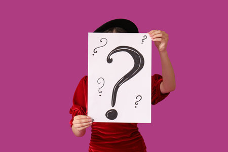 Young woman holding paper sheet with question marks on purple backgroundの写真素材
