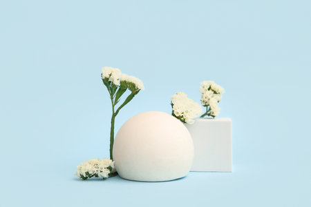 Composition with beautiful flowers and plaster podium on blue backgroundの写真素材