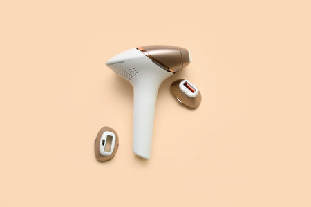 Modern photoepilator with attachments on beige background