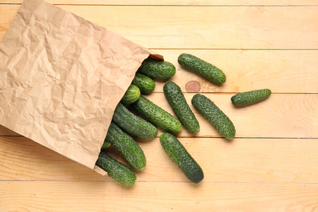 Paper bag with fresh cucumbers on wooden backgroundの写真素材