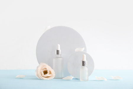 Composition with bottles of essential oil and beautiful eustoma flower on light backgroundの写真素材