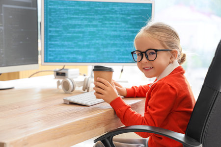 Cute little programmer girl with cup of coffee in officeの写真素材
