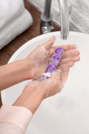 Woman washing vibrator over sink, closeupの写真素材