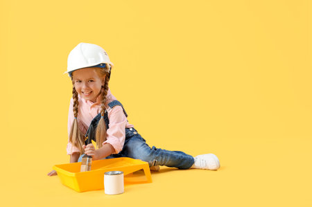 Cute little builder with painting brush on yellow backgroundの写真素材