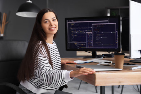 Pretty young female programmer with laptop in officeの写真素材