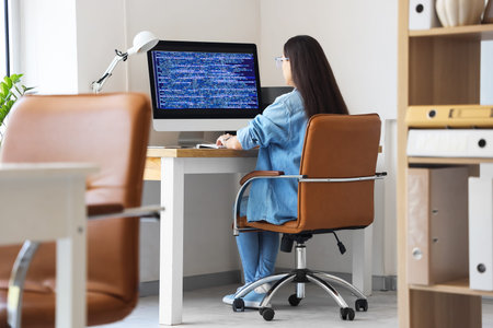 Pretty young female programmer working in office